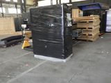 un grand réfrigérateur noir dans un entrepôt où se trouvent des palettes de bois