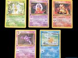 Quatre cartes Pokémon différentes sont représentées sur une surface noire.