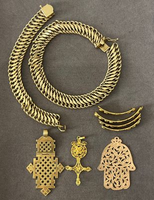 une collection de bijoux en or comprenant une hamsa, une croix et un pendentif
