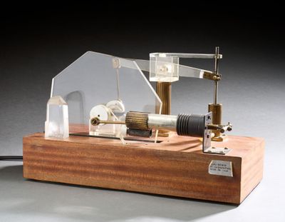 une petite maquette de machine à vapeur posée sur un socle en bois
