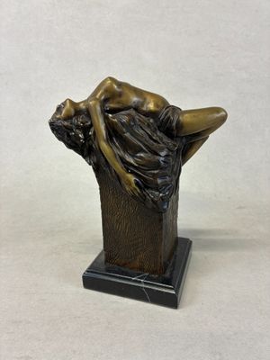 bronze statue of a woman laying on a tree trunk