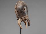 a wooden mask with horns on a stand on a gray background