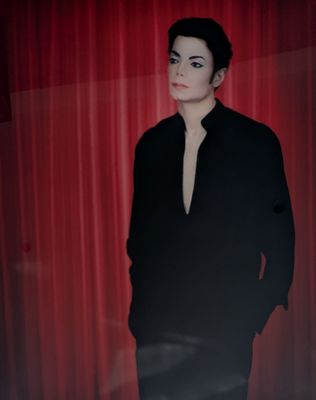 Michael Jackson devant un rideau rouge, les mains dans les poches