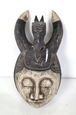 gros plan d'un masque en bois sur une surface blanche