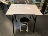 a white table with a black stool in front of it
