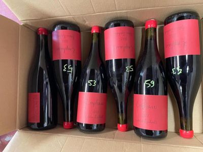 six bottles of red wine in a cardboard box on a table