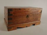 une petite boîte en bois munie de poignées en métal, posée sur une table