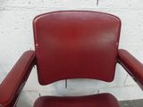 a red leather chair with a foot rest on a concrete floor