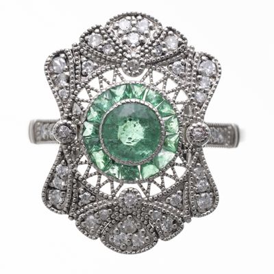 gros plan d'une bague avec une pierre verte entourée de diamants