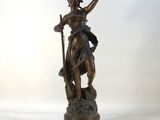 bronze statue of a woman holding a bird on a pedestal