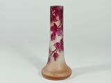a close up of a vase on a white surface with pink flowers