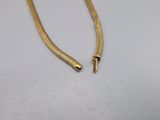 a gold necklace with a long chain on a white surface