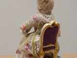 a figurine of a woman sitting on a chair