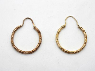 une paire de boucles d'oreilles en or sur fond blanc