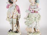 pair of porcelain figurines of a man and a woman with a dog