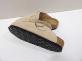 pair of beige sued slippers with black soles on a white surface