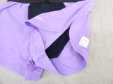 purple and black shorts laying on a bed with a white pillow