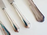four silverware pieces on a white table with a knife and a fork