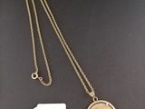 a gold necklace with a coin and a tag on it