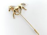 un gros plan d'une broche en forme de cheval en or sertie de diamants, sur fond blanc