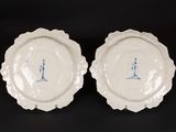 two white plates with blue designs on them sitting on a black surface