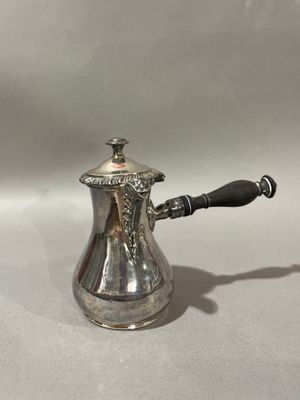 une cafetière ancienne en argent avec une poignée noire sur une surface blanche