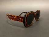 leopard print sunglasses with black lenses on a gray surface