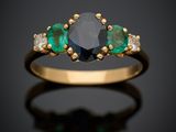 une bague sertie d'un diamant noir et d'une émeraude sur fond noir