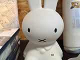 un lapin blanc assis sur une table, à côté d'un rouleau de papier toilette