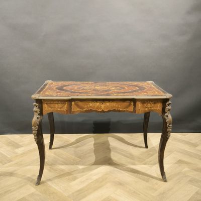 an old wooden table with a marble top on a wooden floor
