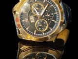 a gold watch with a black face on a black surface