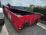 une benne rouge garée sur un parking à côté d'une camionnette blanche