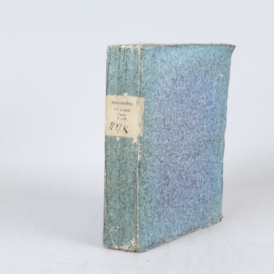 un vieux livre posé sur une table blanche à côté d'un mur blanc