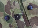 a close up of a camouflage shirt with buttons