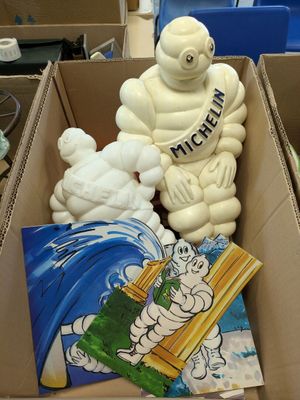 a cardboard box with a statue of a man and a teddy bear in it