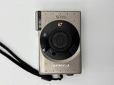 a silver camera sitting on a white surface with a black strap