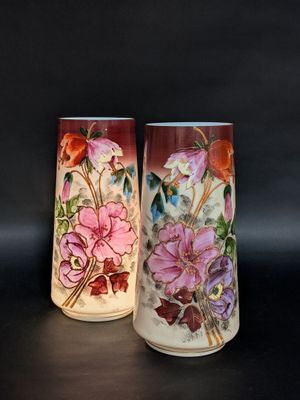 deux vases sur lesquels sont peints des fleurs sur un fond noir
