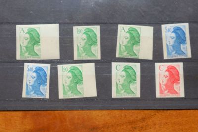 plusieurs timbres de différentes couleurs posés sur un papier noir, posé à son tour sur une table en bois
