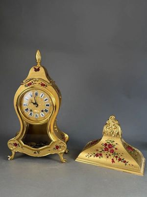 a gold clock sitting next to a small gold clock on a table