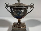 an antique silver plated trophy on a stand with a bird on top