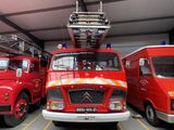 Trois camions de pompiers rouges sont garés dans un garage équipé d'une échelle.