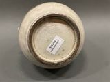 a close up of a white vase with a tag on it