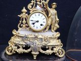 a gold clock with a glass dome on top of it