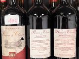 several bottles of red wine sit on a shelf in a store