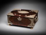 an ornate wooden box with metal decorations on top of a gray surface