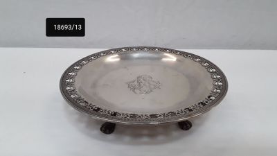 a silver plate on a stand on a white surface
