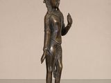 bronze statue of a person holding a bird on a glass table