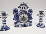 three blue and white vases and a clock on a table