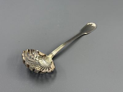 une cuillère ancienne en argent posée sur une surface grise