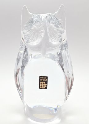 une figurine de chouette en verre posée sur une surface blanche